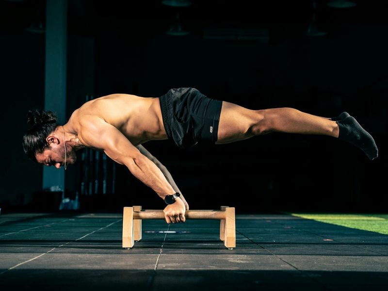 A man performing a controlled bodyweight exercise with intense focus.