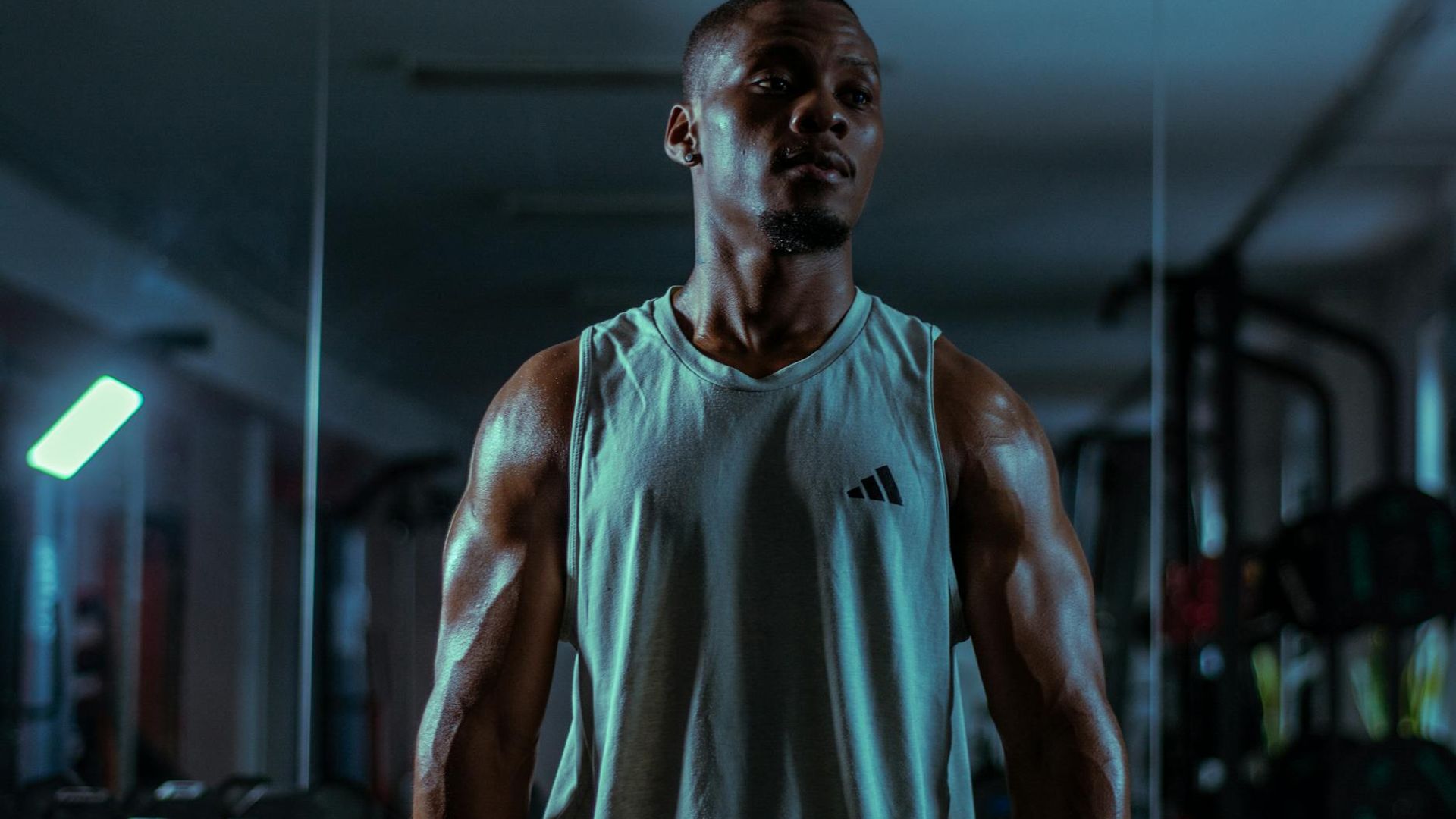 Man in a focused athletic stance in a minimalist dark gym.