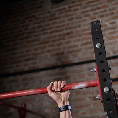 Man's hands gripping a pull-up bar, showing strength and control.